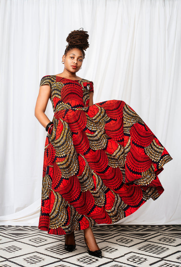 Woman wearing a red and black patterned dress against a white curtain background