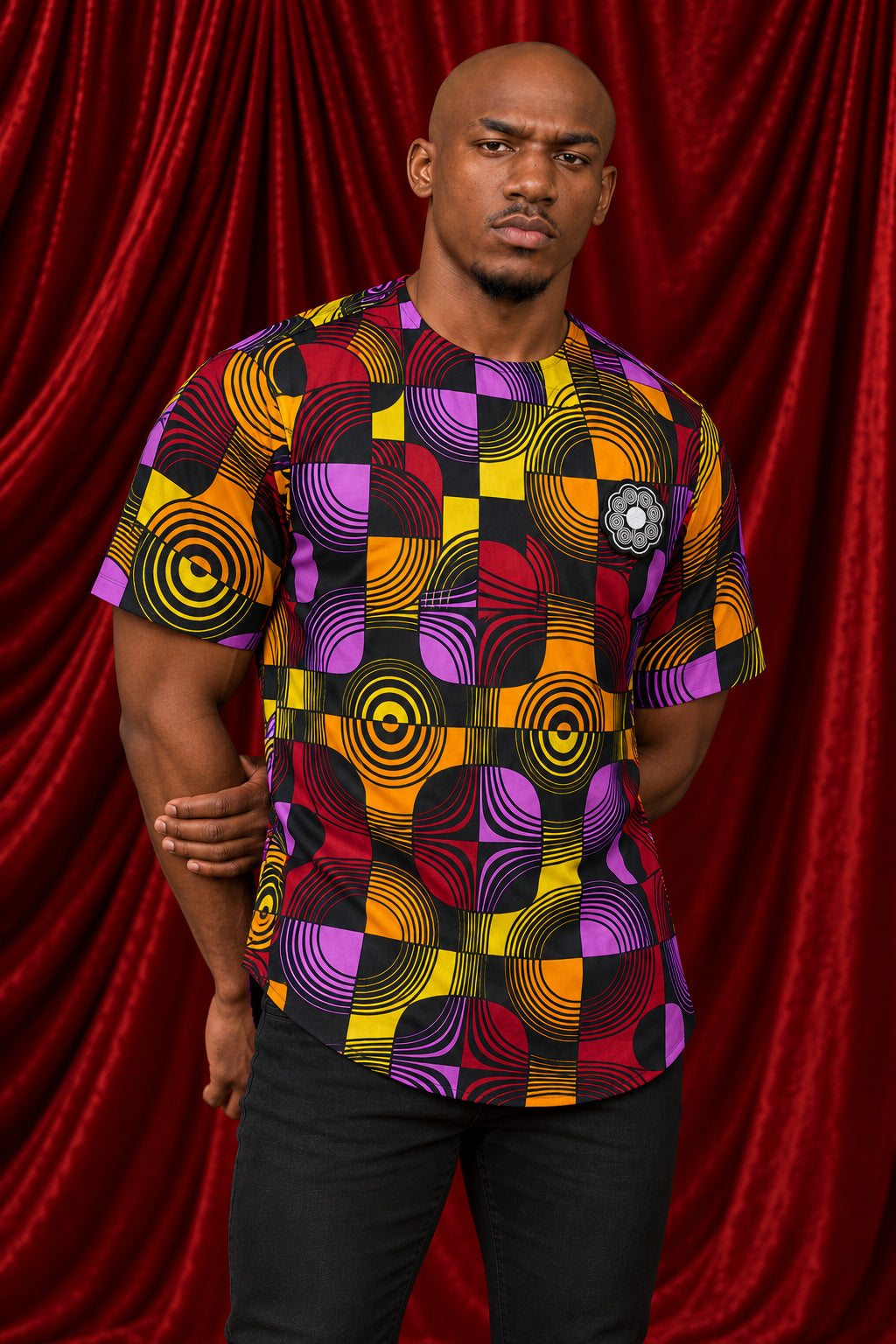 Front view of the Chepa Lerato Print Tee in purple, gold and magenta circles, worn with black trousers