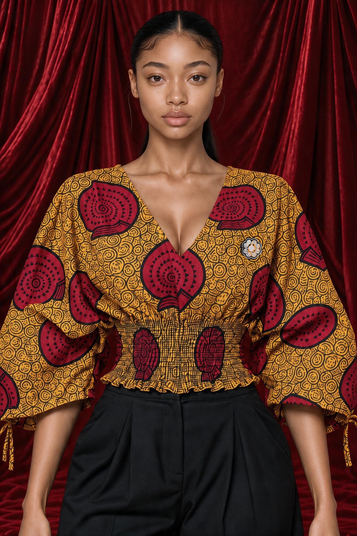 Langa Smocked Wrap Top in the ochre and red rosette print, front view, worn with black trousers